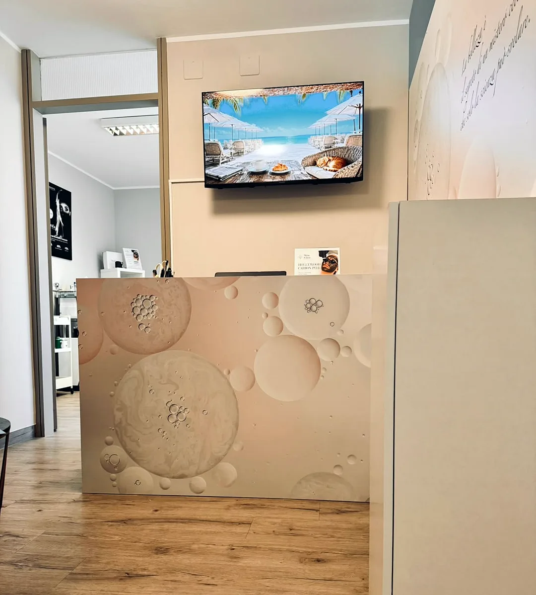 Reception di Skin Clinic con bancone decorato a motivi circolari e televisore alle spalle